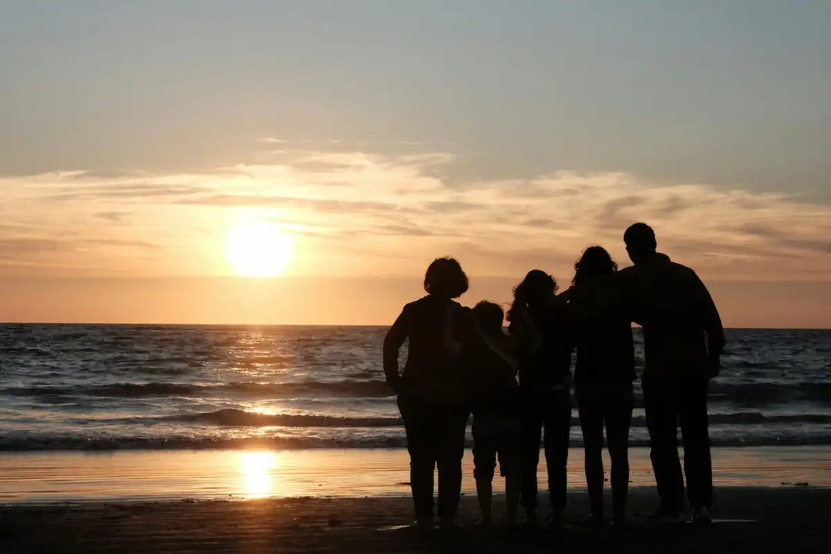 Sırtı dönük aile gün batımında, 12–18 yaş ergenlik döneminde çocukları ile beraber, aile iletişimi ve ebeveyn yaklaşımı temsil eden resim